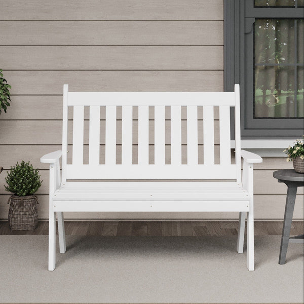 White bench on a porch with plants and a window in the background